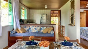 Un rincón acogedor con sofá, mesa de comedor para dos personas y cocina al fondo.