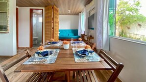 Un comedor con una mesa de madera dispuesta para cuatro personas, un sofá color turquesa y un televisor al fondo.