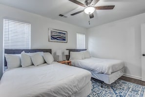 Quarto com duas camas, ventoinha no teto, um quadro e tapete estampado.