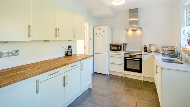 A modern kitchen with white cabinets, a wooden countertop, a built-in microwave, and a stainless steel range hood. - 5 bedroom accommodation in Bransgore, near Christchurch (Bransgore, near Christchurch)
