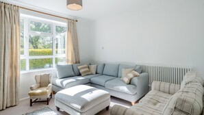 A living room with a sectional sofa, a chair, a small ottoman, and a radiator. - 5 bedroom accommodation in Bransgore, near Christchurch (Bransgore, near Christchurch)