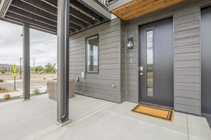 Ein modernes Haus mit grauem Anstrich, einer schwarzen Tür und der Hausnummer 13 an der Wand.