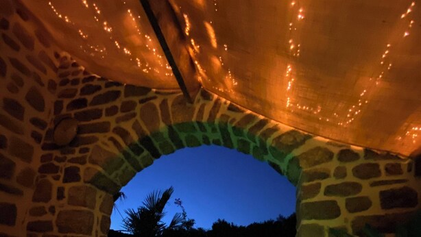 Un arco de piedra que conduce a una zona de piscina climatizada con iluminación verde.
