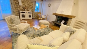 Una sala de estar acogedora con una pared de piedra, una chimenea y un sofá blanco con cojines estampados.