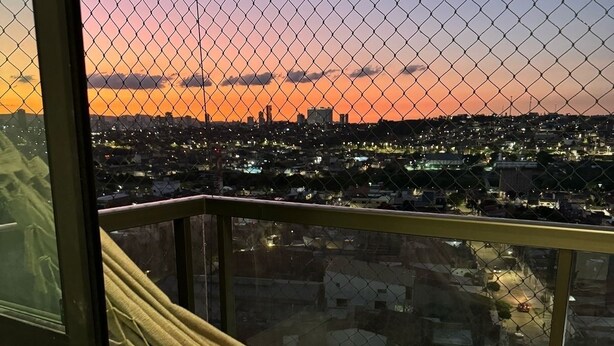 Een hangmat op een balkon met uitzicht op een stadsgezicht bij zonsondergang.