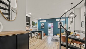 Een moderne keuken met een eethoek, een trap en een zithoek met een bank en stoelen.