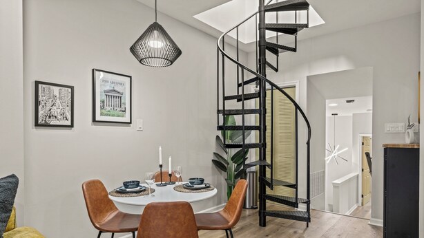 Een eethoek met een ronde tafel, stoelen en een wenteltrap.