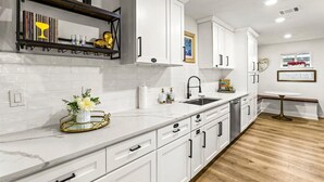 A modern kitchen with white cabinets, a marble countertop, and a wooden floor. - Spacious 4-bedroom house with AC, WiFi, Houston Hideaway 10 min to NRG (Houston)