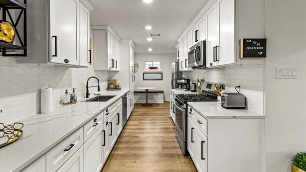 A modern kitchen with white cabinetry, a central island, and a microwave. - Spacious 4-bedroom house with AC, WiFi, Houston Hideaway 10 min to NRG (Houston)