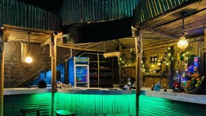 Eine Bar mit Hockern, einer Theke und grüner Neonbeleuchtung.