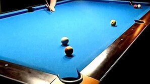 Ein Billardtisch mit Kugeln und einer Person beim Spielen.