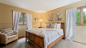 A bedroom with a wooden bed, a chair, and two windows with curtains. - Lanfyne Ayr / Views / Gameroom (Waynesville)