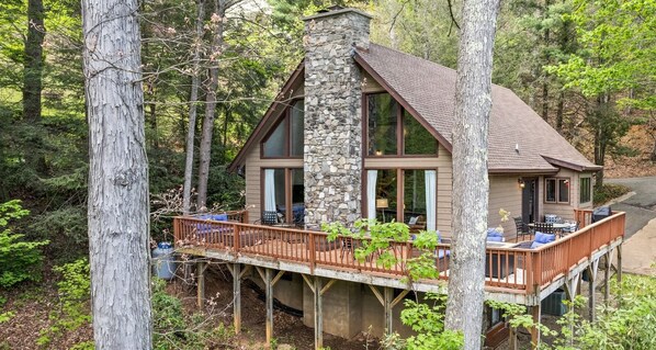 A cabin with a stone chimney, large windows, and a wooden deck. - Lanfyne Ayr / Views / Gameroom (Waynesville)