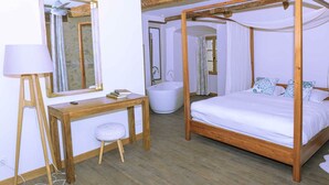 Un dormitorio con una cama con dosel, un escritorio de madera con una silla, un tocador con espejo y una bañera.