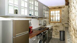 Una cocina compacta con refrigerador de acero inoxidable, encimera de madera y lavadora.
