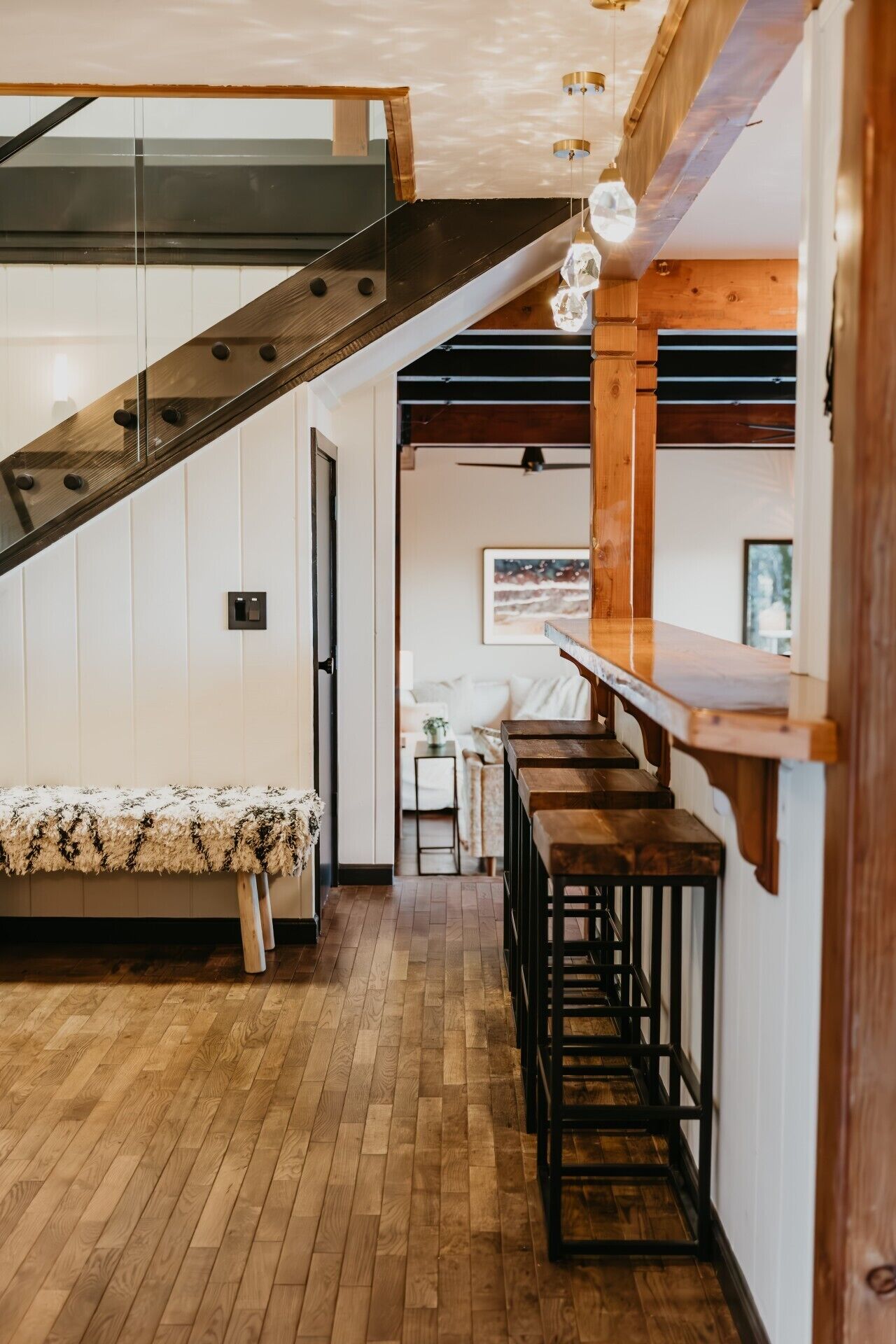 Una escalera con escalones de madera y barandillas metálicas, que conduce a una zona elevada con techo de cristal.