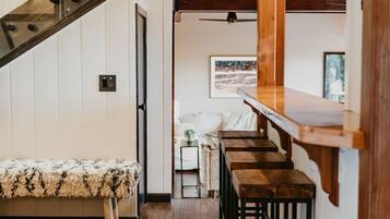 Una escalera con escalones de madera y barandillas metálicas, que conduce a una zona elevada con techo de cristal.