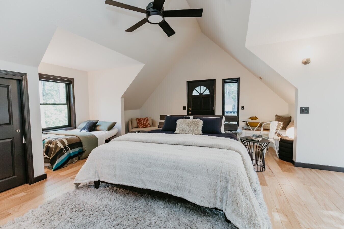 A bedroom with a large bed, a ceiling fan, a desk, and a chair.