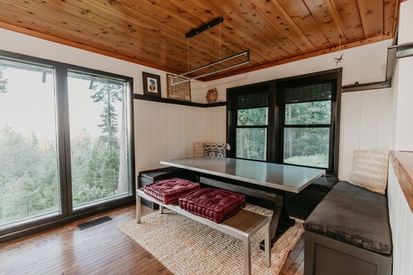 Una cocina moderna con techo de madera, ventanas amplias, una mesa de comedor y estufa integrada.