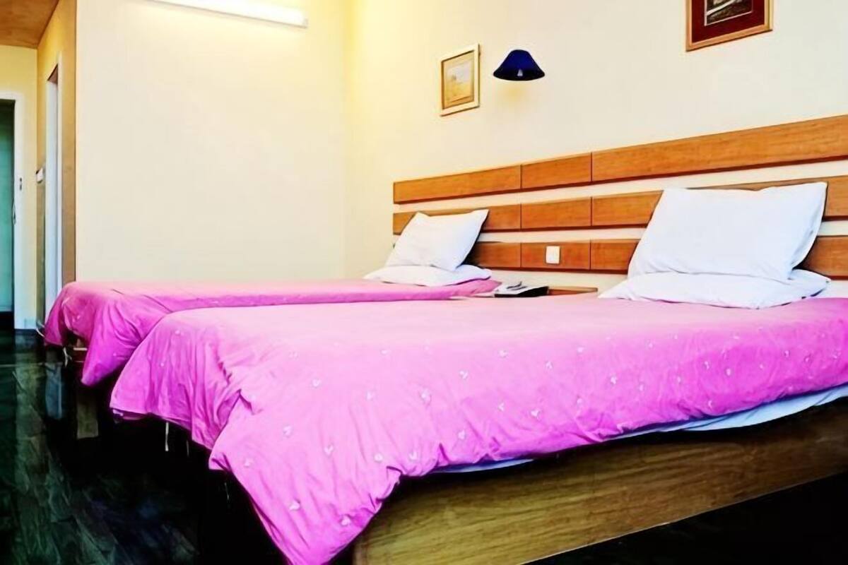 A hotel room with two beds, wooden headboards, and a nightstand.