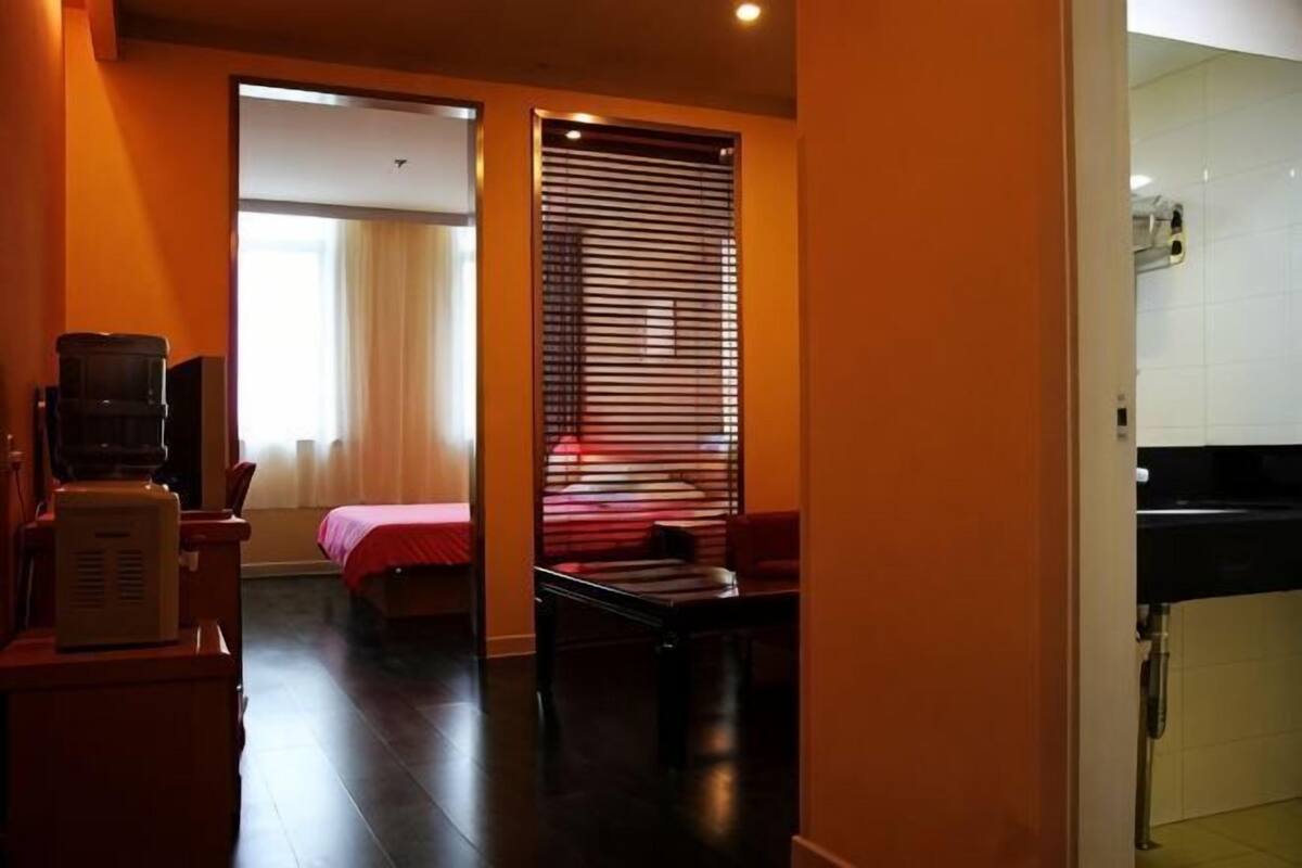 A hotel room with a bed, a desk, a TV, and a kitchenette.