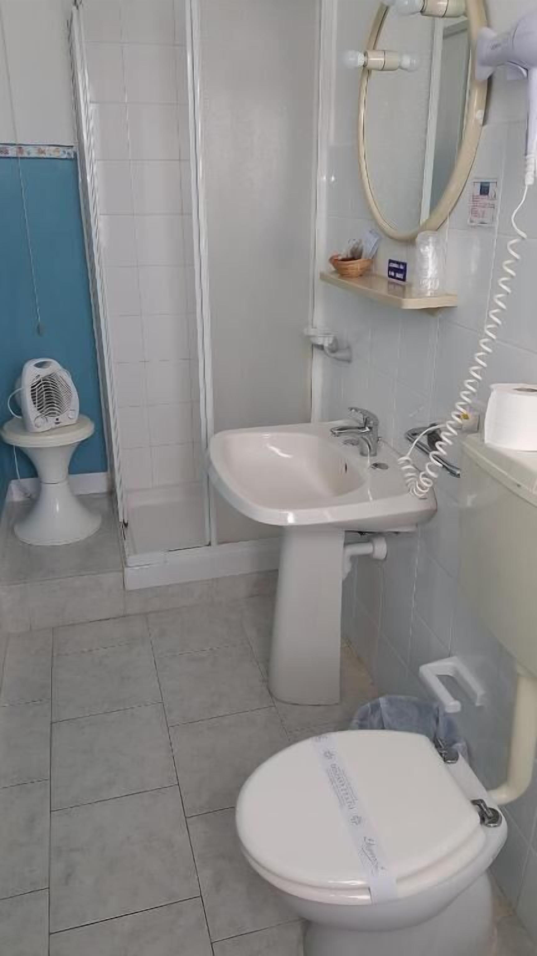 A bathroom with a toilet, sink, and shower.
