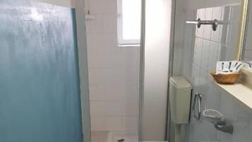 A narrow bathroom with a toilet, sink, and a window.