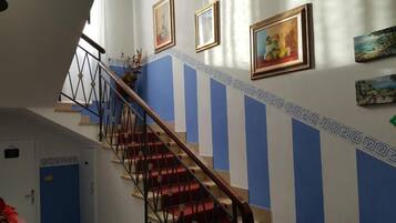 A staircase with red carpeted steps, blue and white wall panels, and framed artwork.