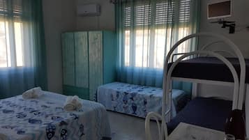 Ein Zimmer mit zwei Betten, einem Schrank und einem fensterbepflanzten Fenster.
