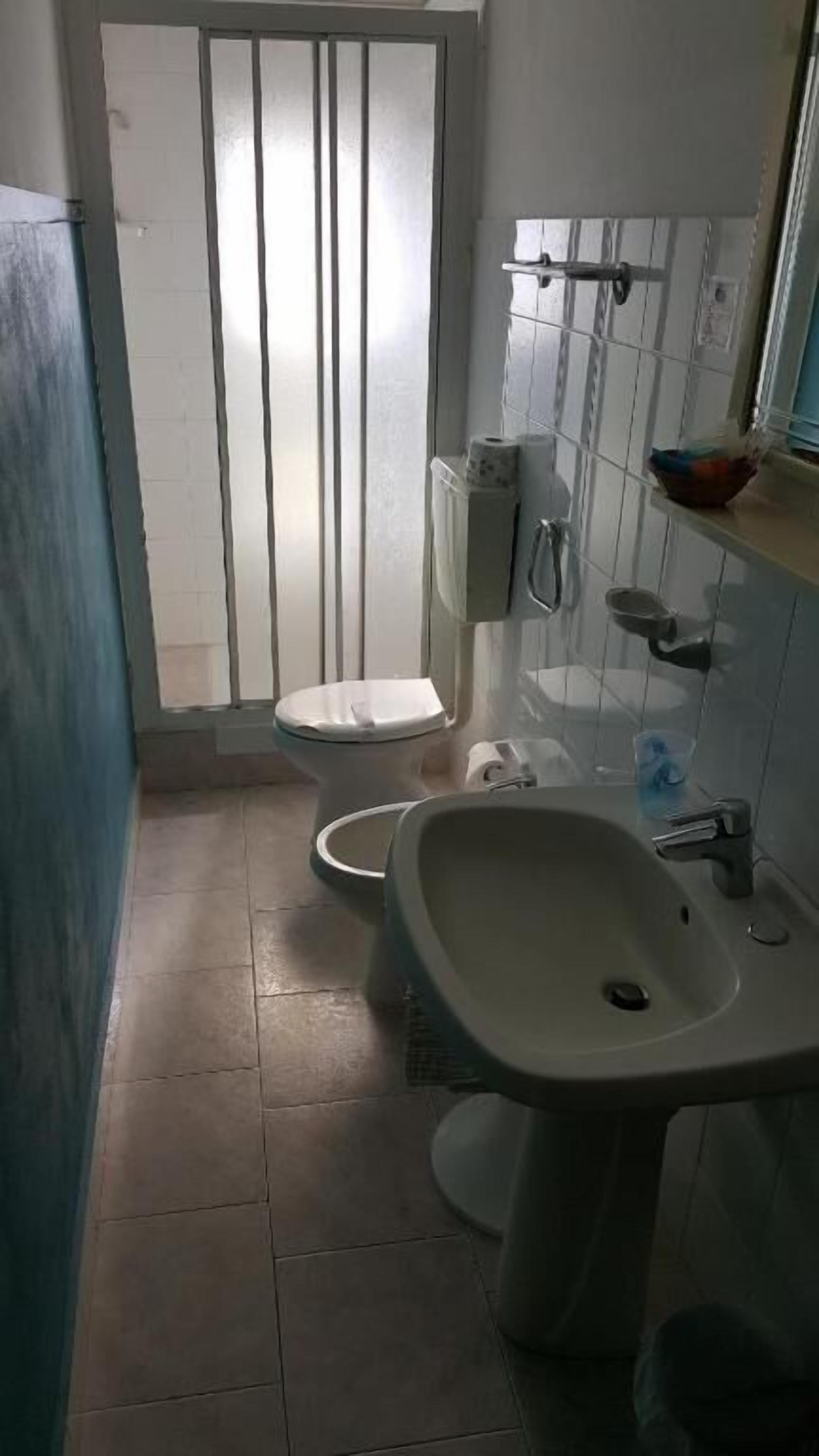 A small bathroom with a toilet, sink, and a shower area.