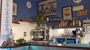 Un coin bar avec une machine à café, des étagères remplies de bouteilles, une horloge et un tableau encadré au mur.