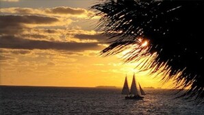 A sunset over the ocean with a sailboat. - Charming studio in Key West -Close to Duval.  Beautiful Pool area. (Key West)