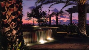 A waterfall feature with a view of palm trees and a sunset. - Charming studio in Key West -Close to Duval.  Beautiful Pool area. (Key West)