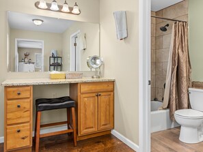 Une salle de bain avec un meuble-lavabo en bois, un miroir, des toilettes et un espace douche.