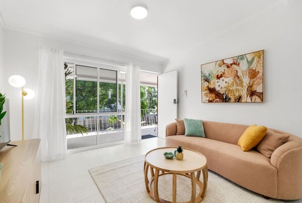 A modern living room with a sofa, a round coffee table, and a large window with curtains.