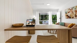 Un comedor moderno con una mesa de madera, dos sillas, una computadora portátil y un bol.