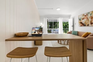 A modern dining area with a wooden table, two chairs, a laptop, and a bowl.