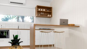 Una cocina moderna con armarios blancos, encimera de madera, una computadora portátil y dos taburetes de bar.