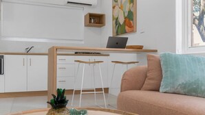Una cocina moderna con armarios blancos, una computadora portátil sobre una barra de madera y un taburete.