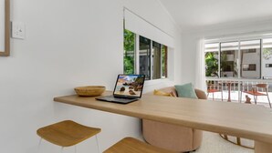 A modern kitchen with a wooden countertop, a laptop, and two stools.