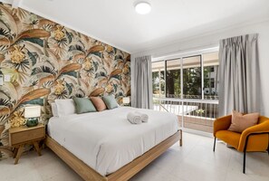 Une chambre à coucher avec un lit, une table de chevet, une lampe et une chaise.
