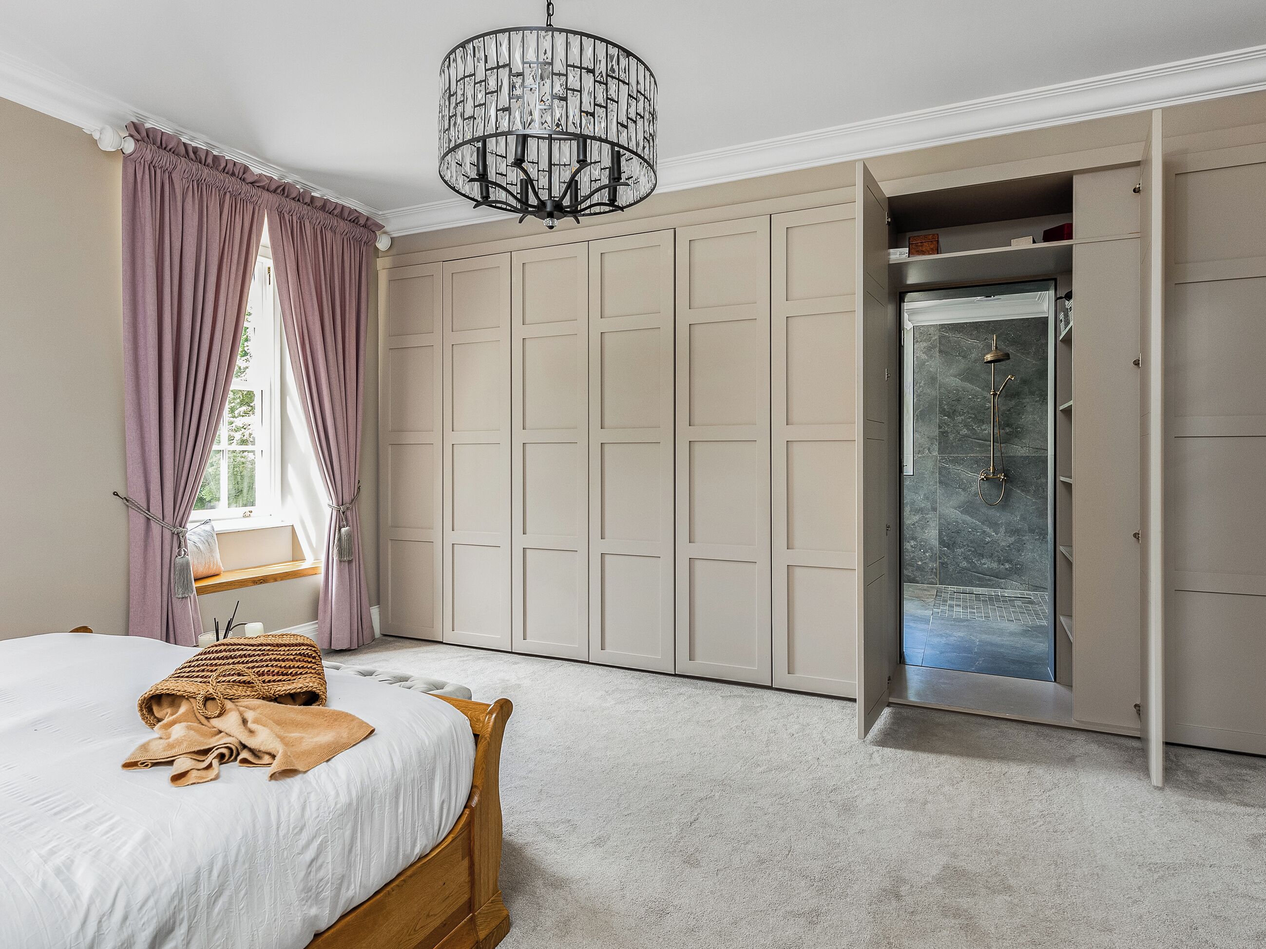 Une chambre à coucher avec un lit, une armoire, une douche et un lustre.