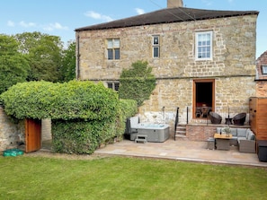 A stone house with a garden patio, a hot tub, and outdoor seating.