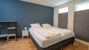 Une chambre à coucher comprenant un lit, une table de chevet, une lampe et une étagère.