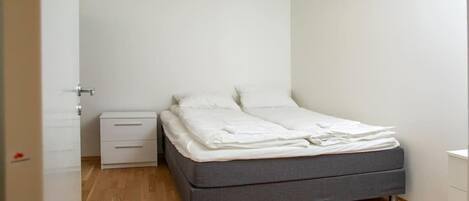 A bedroom with a bed, a nightstand, and a dresser.