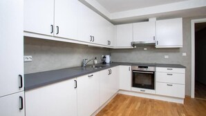Une cuisine moderne avec des meubles blancs, un plan de travail gris et un four encastré.