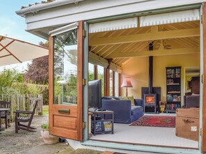 Un espacio abierto tipo sala de estar con sofá, televisión, chimenea y estantería.