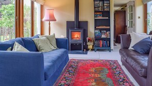 A cozy living room with a fireplace, blue sofas, a bookshelf, and a rug.