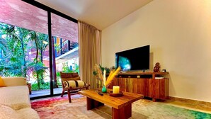 A living room with a large window, a sofa, a wooden coffee table, and a TV on a wooden stand.