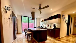 A modern kitchen with a central island, dark cabinetry, and a large window providing natural light.